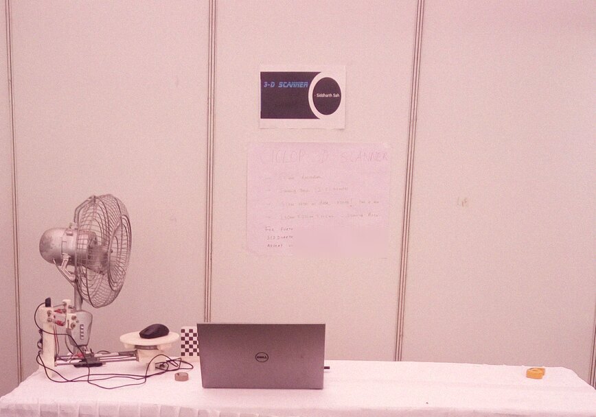 Our Quark booth: the scanner with its checkerboard calibration target on a white tablecloth, the handwritten spec poster on the wall