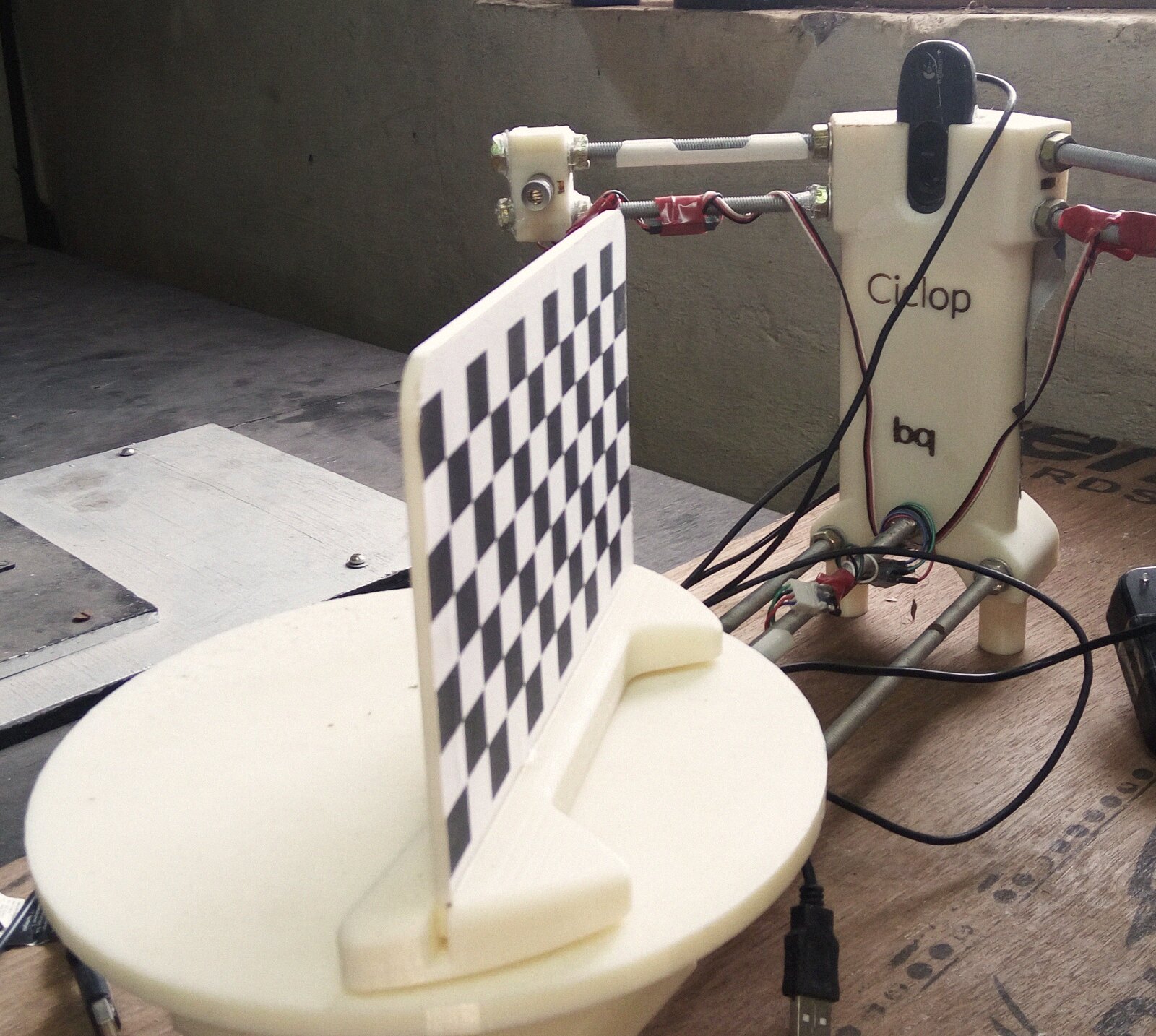 The checkerboard calibration target standing on the turntable, the webcam and both laser mounts facing it
