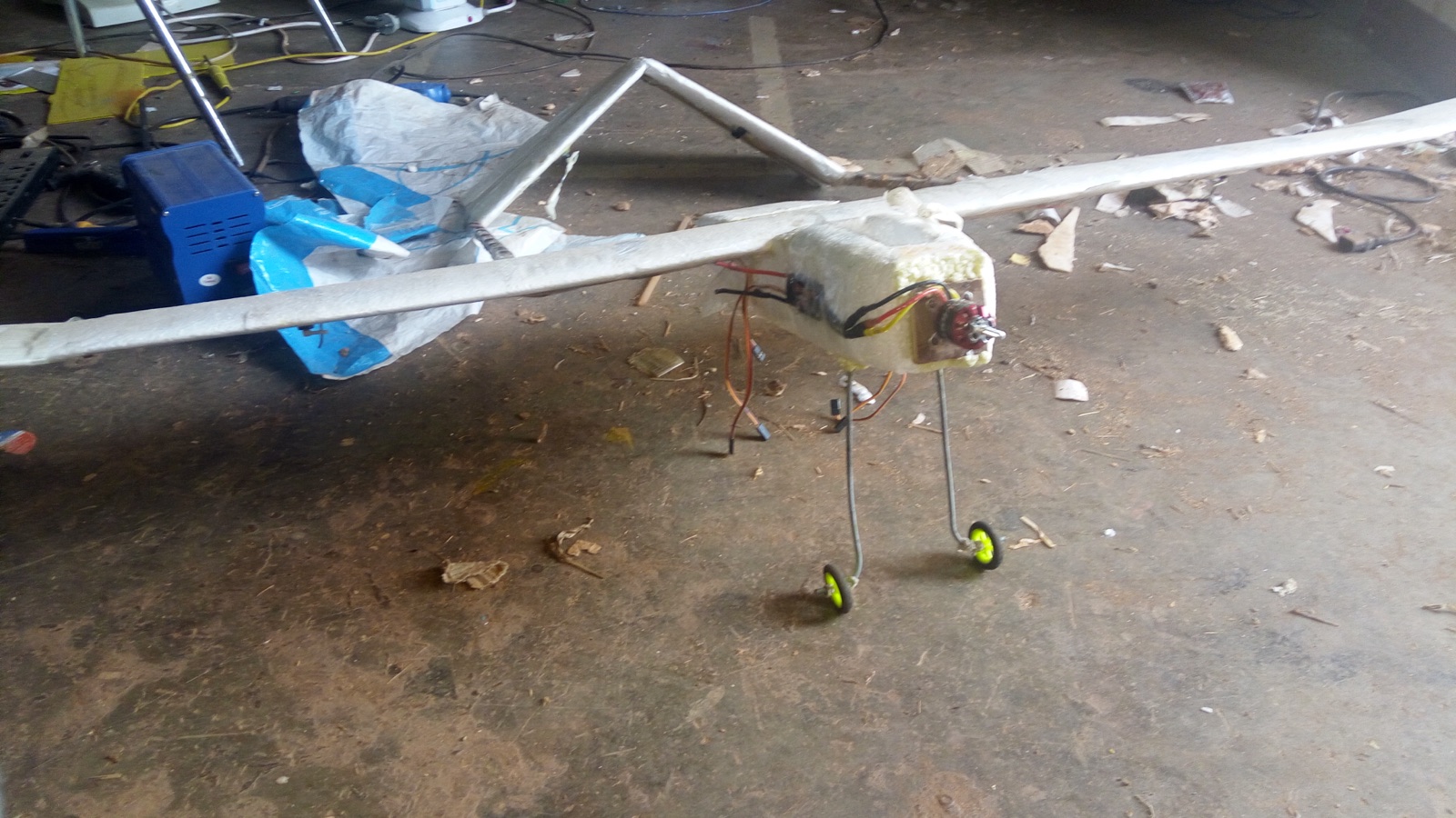 A scratch-built foam plane in the workshop: thermocol fuselage, taped wing, landing gear bent from steel wire with salvaged wheels
