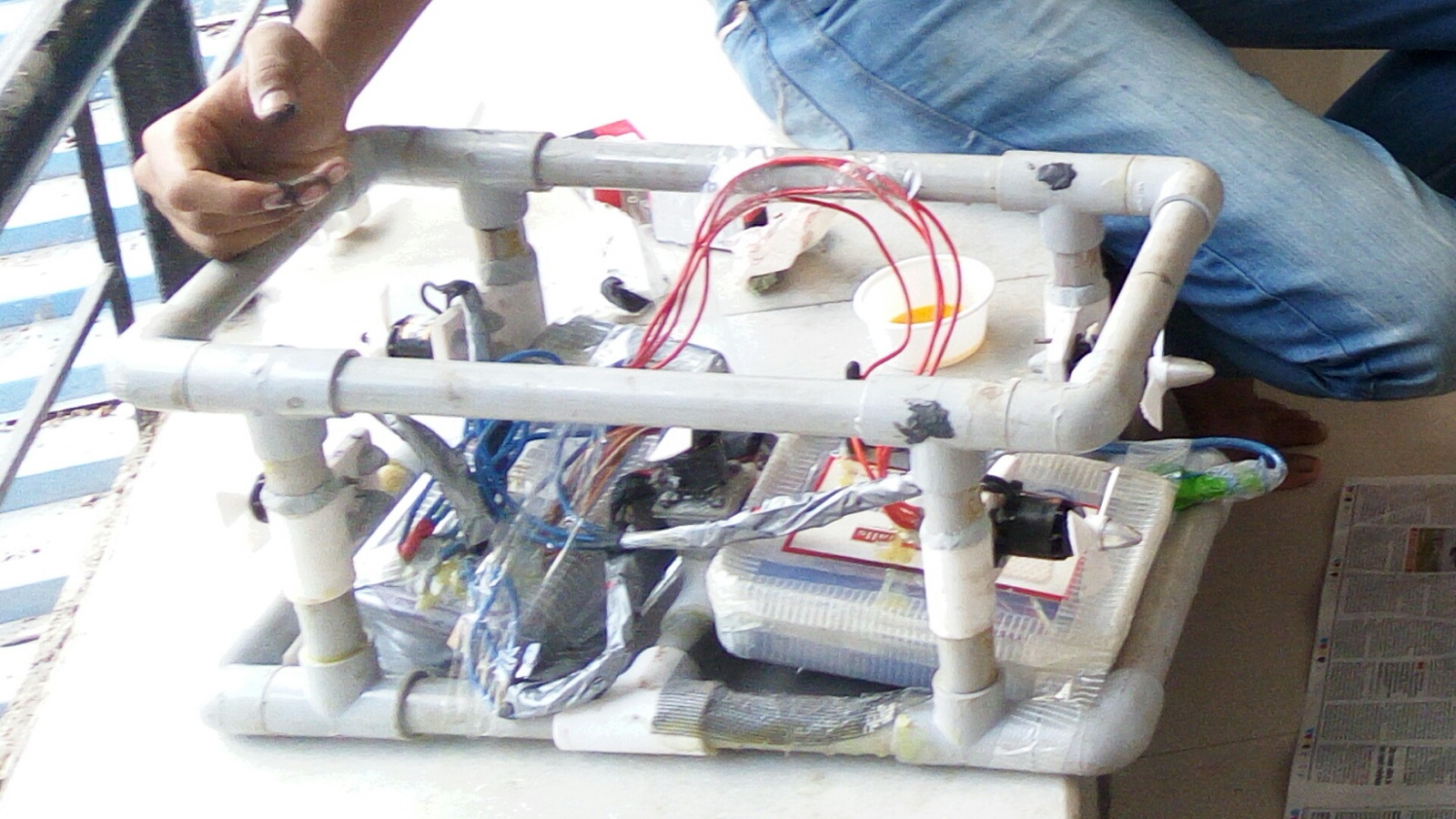An early prototype frame during a January test: motors sealed in taped plastic, food containers pressed into service as dry boxes, and epoxy putty on the joints