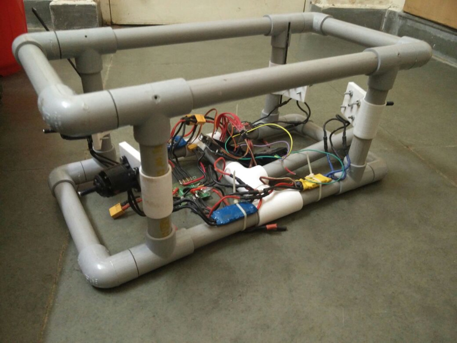 Three-quarter view of the assembled PVC frame with a corner thruster, ESCs, and wiring visible